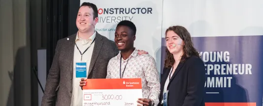 Steven Kibande (middle), student of Mbarara University, Uganda, won first place with his start-up Kanga Care at the Young Entrepreneur Summit, which was organized by Oscar Kirkwood (left) and Thea Mischel (right). (Source: Constructor University)