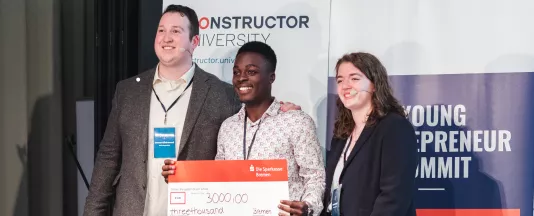 Steven Kibande (Mitte) von der Mbarara Universität in Uganda, holte mit seinem Start-up Kanga Care den ersten Platz beim Young Entrepreneur Summit, organisiert von Oscar Kirkwood (li.) und Thea Mischel (re.). (Quelle: Constructor University)