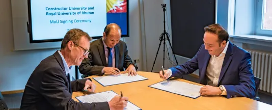Provost Dr. Frazer Cairns, Vice Chancellor Dasho Chewang Rinzin and Chancellor Turgut Tülü (from left to right) signing the first MoU between Constructor University and the Royal University of Bhutan.