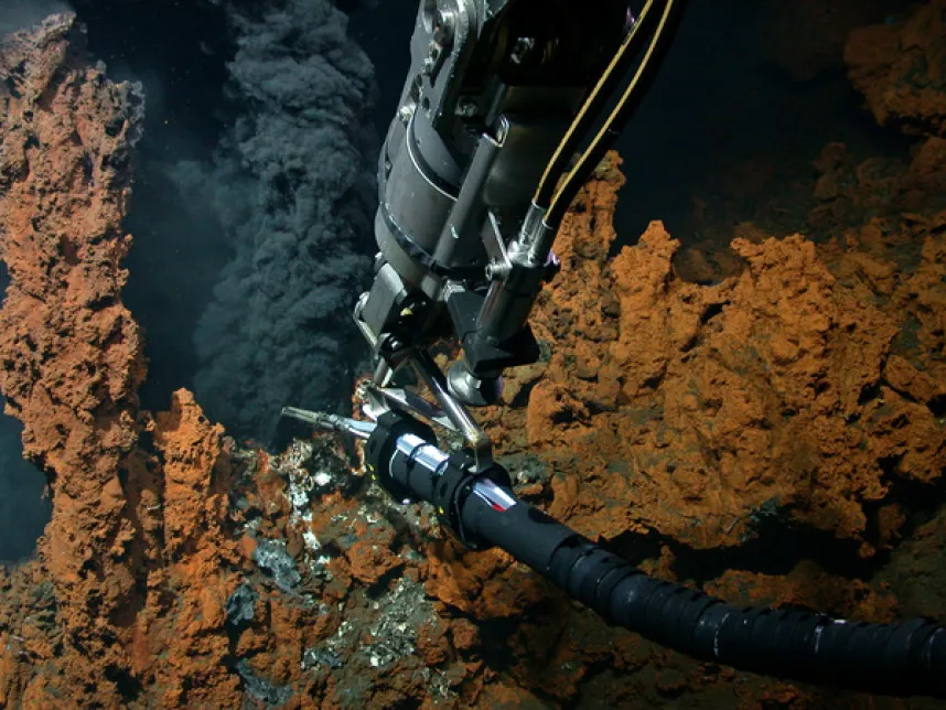 A hydrothermal vent on the Mid-Atlantic Ridge. Hot, mineral-rich fluids are distributed throughout the ocean via the dispersion cloud, known as the plume. The photo was taken during the M190 research expedition with the MARUM-QUEST4000 remotely operated vehicle. The arm of the robot holds a temperature lance into the plume to measure the temperature there. Photo: MARUM – Center for Marine Environmental Sciences, University of Bremen.