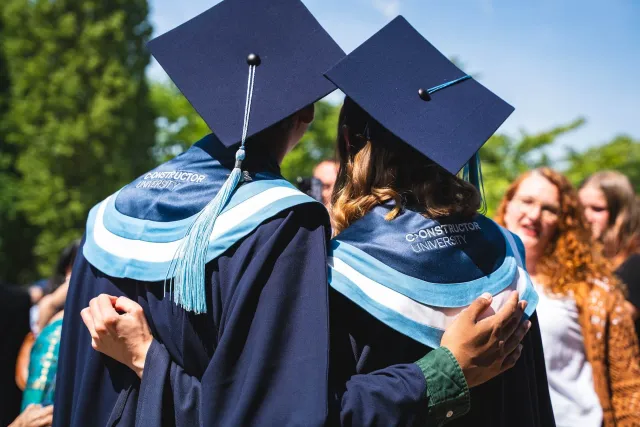 Two Graduated Students Hug – Picture from the Back